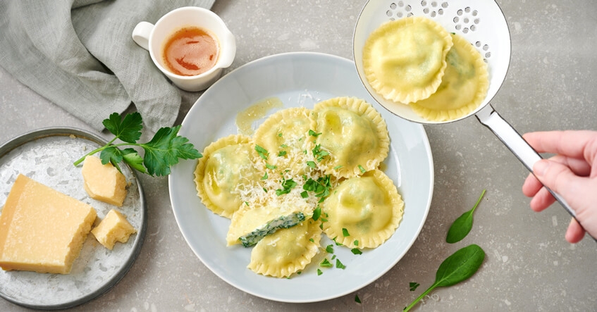 Spinat-Ricotta-Ravioli auf dem Teller und auf einem Schaumlöffel