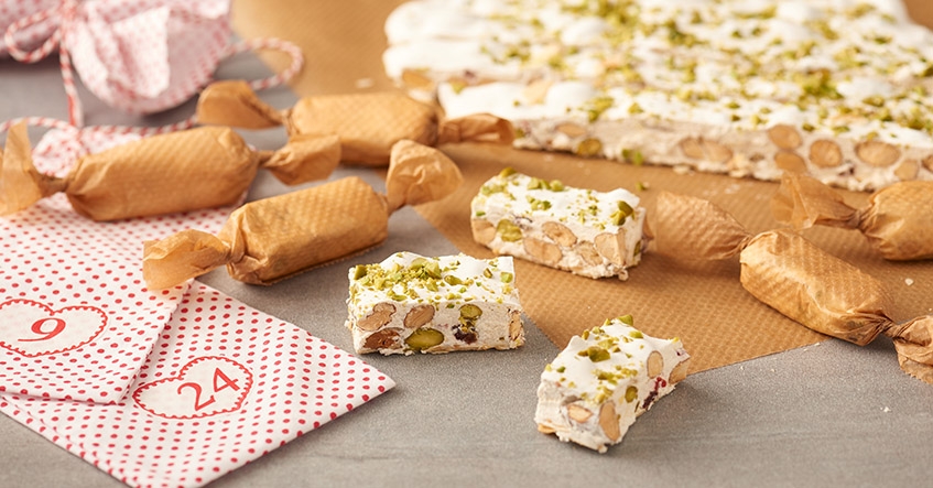 Weißer Nougat oder Turron mit Mandeln und Pistazien auf Backpapier